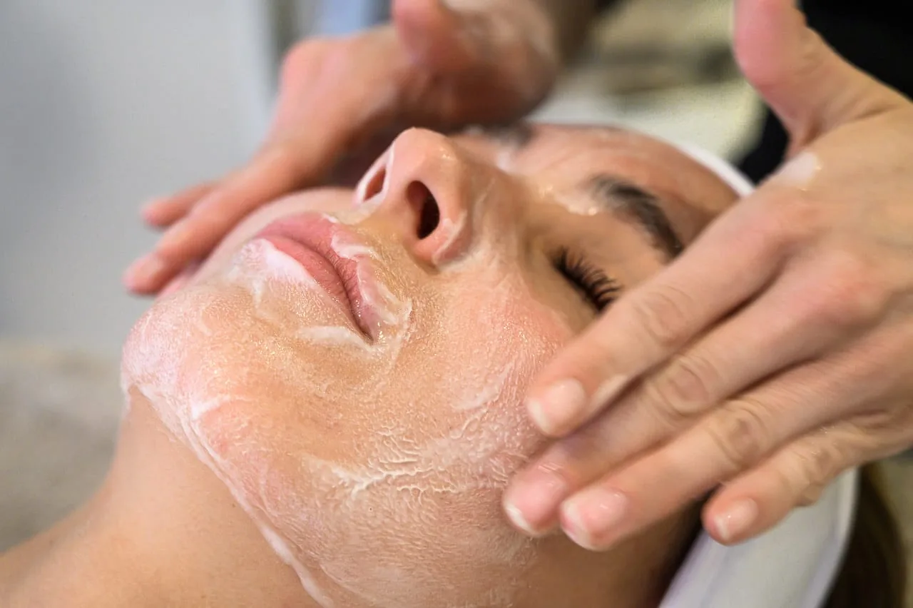 Esthetician massaging moisturizer into a client's face