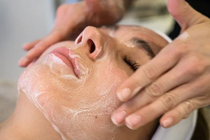 Esthetician massaging moisturizer into a client's face