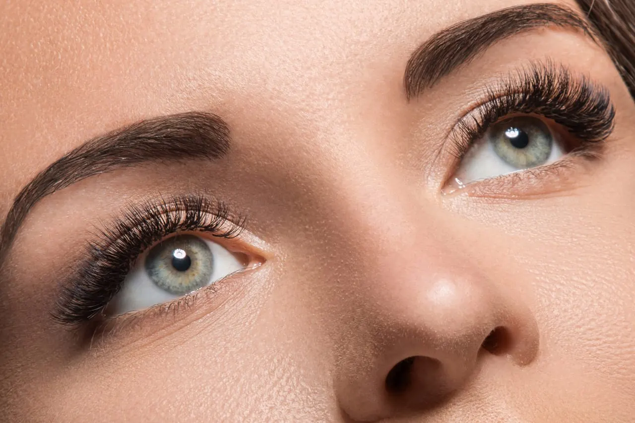 Close-up of two eyes with thick, long eyelashes and shaped eyebrows